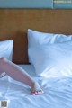 A person laying on a bed with white sheets and pillows.