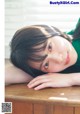 A young woman laying on top of a wooden table.