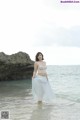 A woman standing in the ocean wearing a white skirt.