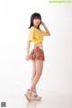 A young woman in a yellow shirt and floral skirt.