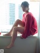 A woman sitting on a window sill next to an apple.