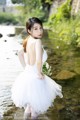 A woman in a white dress standing in a river.