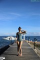 A woman in a blue swimsuit standing on a wooden dock.