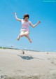 A young girl jumping in the air on a beach.