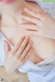 A close up of a woman's breasts with her hands on her breasts.