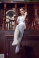 A woman in a white leotard sitting on a wooden staircase.