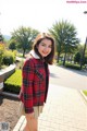 A woman wearing a red and black plaid jacket with a fur collar.