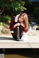 A woman sitting on a wooden dock next to a waterfall.