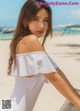 A woman in a white top and pants on a beach.