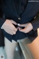 A woman in a business suit is adjusting her tie.