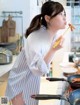 A woman in a kitchen eating a piece of food with chopsticks.