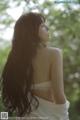 A woman with long brown hair standing in the woods.