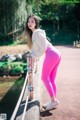 A woman in pink leggings leaning against a railing.