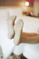 A woman's bare feet on a bed in a hotel room.