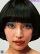 A woman with a black bob with blue eyeshadow on her face.