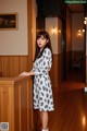 A woman leaning against a wooden wall in a room.