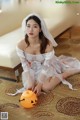 a woman in a white dress sitting on the floor next to a pumpkin