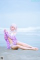 A woman in a purple and white outfit sitting on the beach.