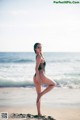 A woman in a black bathing suit standing on a beach.