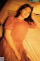 A woman laying on a bed in a pink dress.