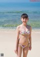 A woman in a bikini standing on a beach.