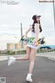 A woman in a white dress holding a skateboard on a road.